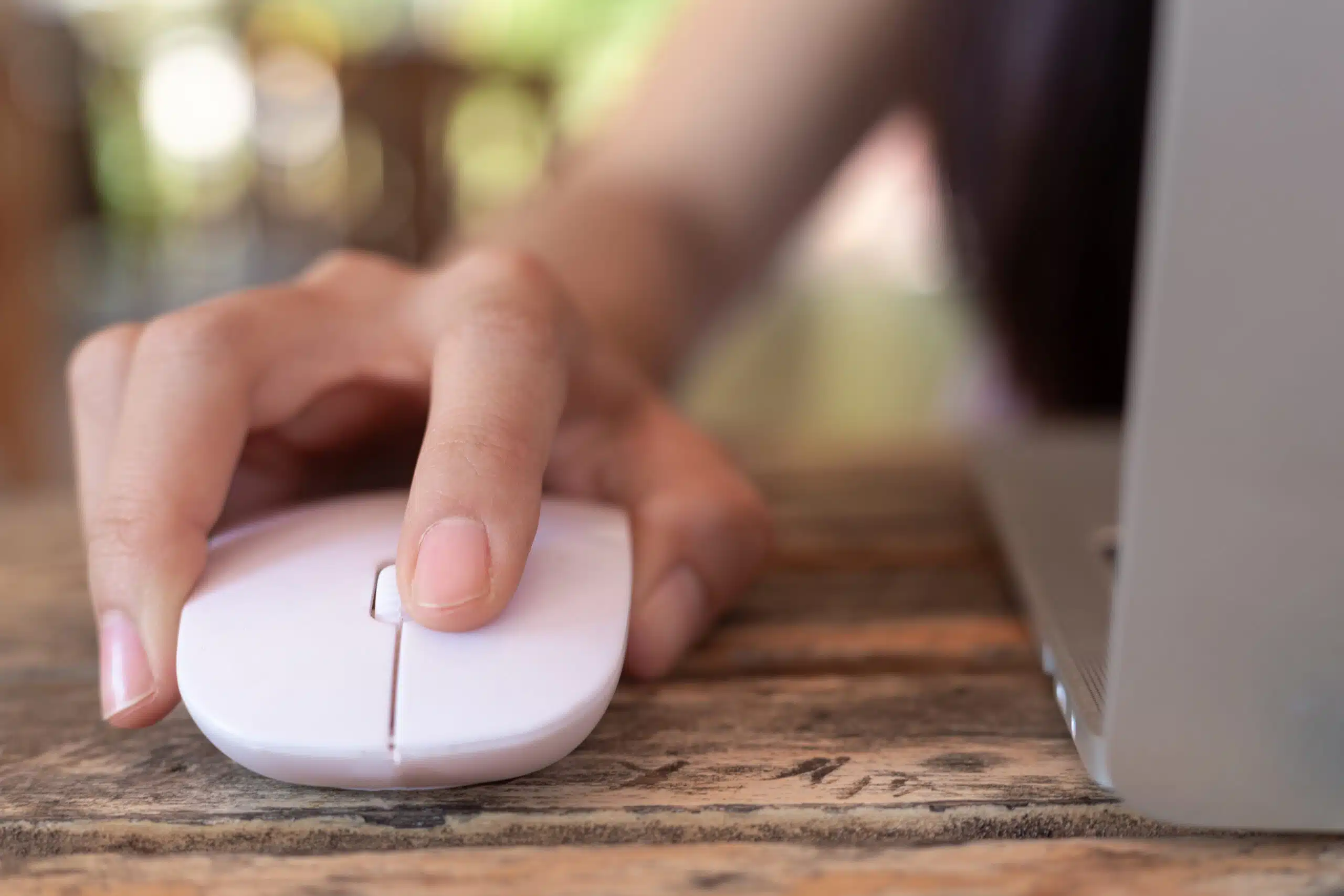 Woman using computer mouse with laptop.